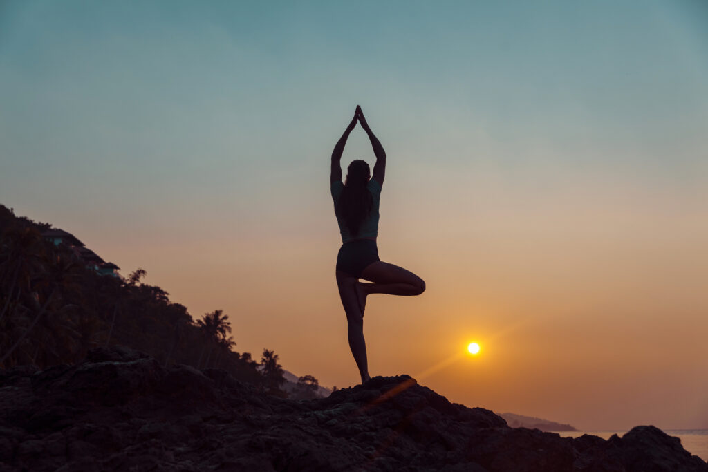 Young woman practicing yoga on the beach