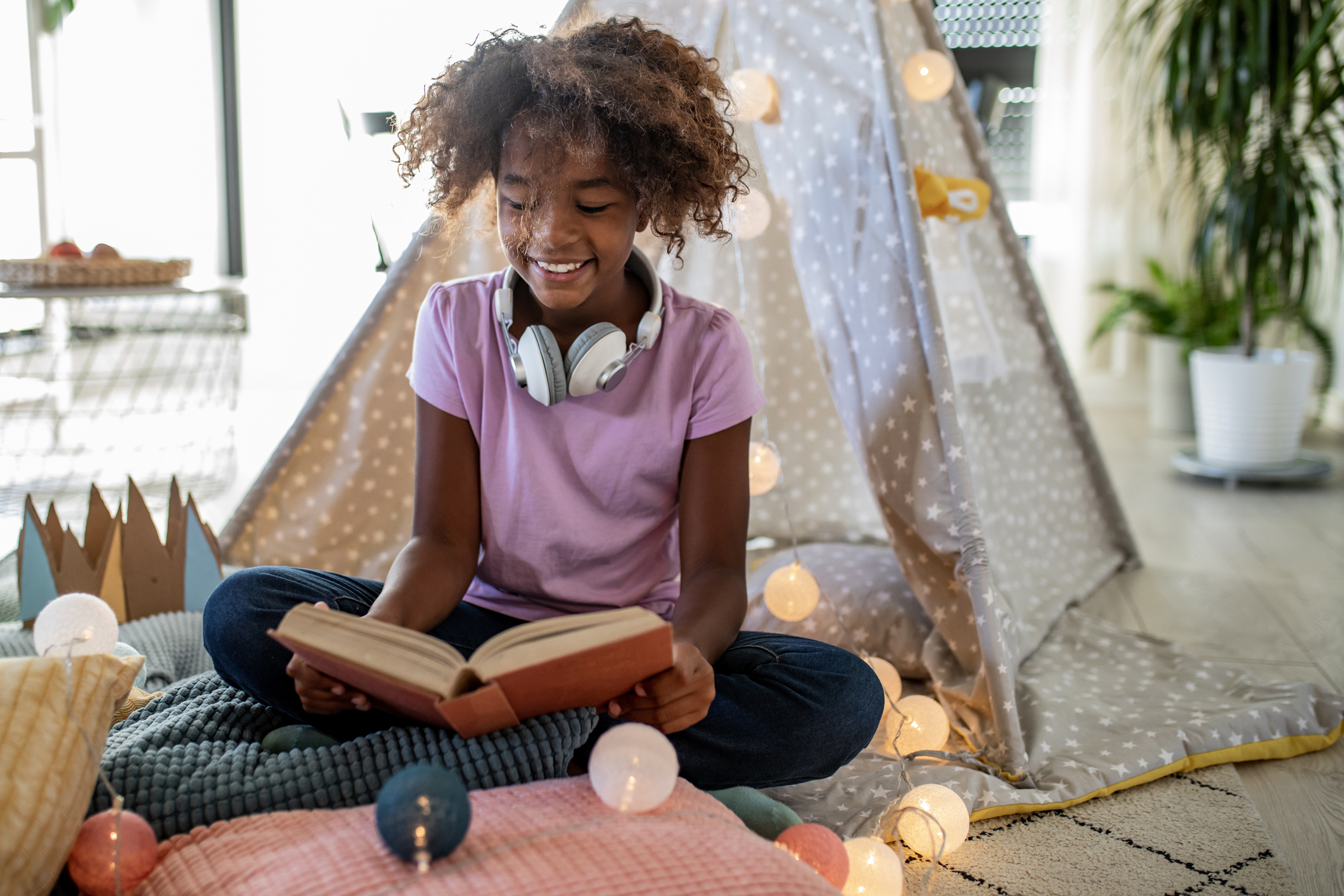 Young African American girl playing on the floor and reading a book