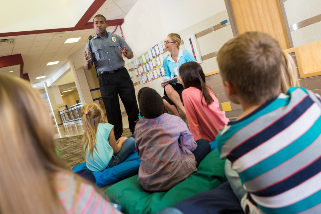 Police or school security officer speaking to young students.